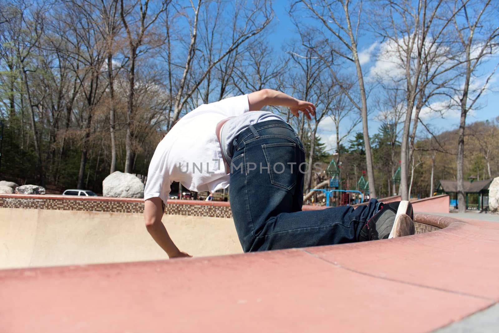 Action shot of a young skateboarder skating sideways against the wall of the bowl at a skate park.