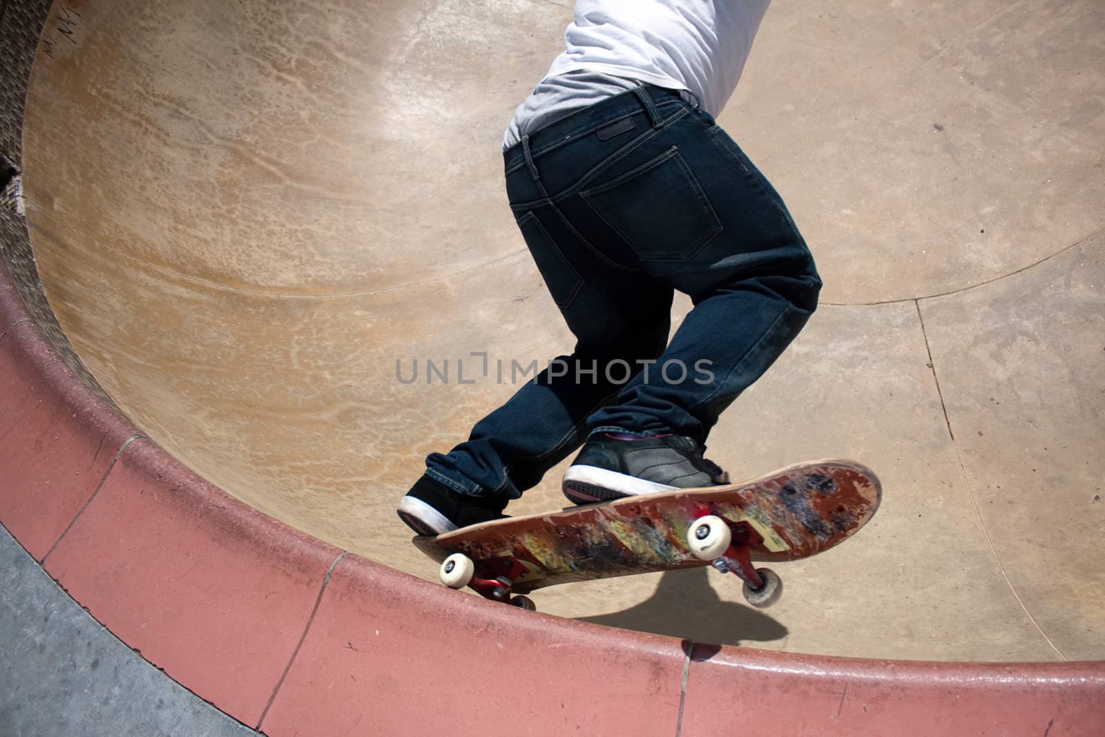 Action shot of a young skateboarder skating sideways against the wall of the bowl at a skate park.