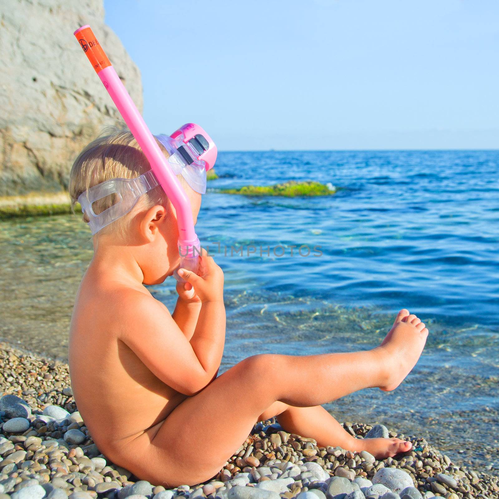 Baby boy on beach with snorkles ready to have a good time swimming