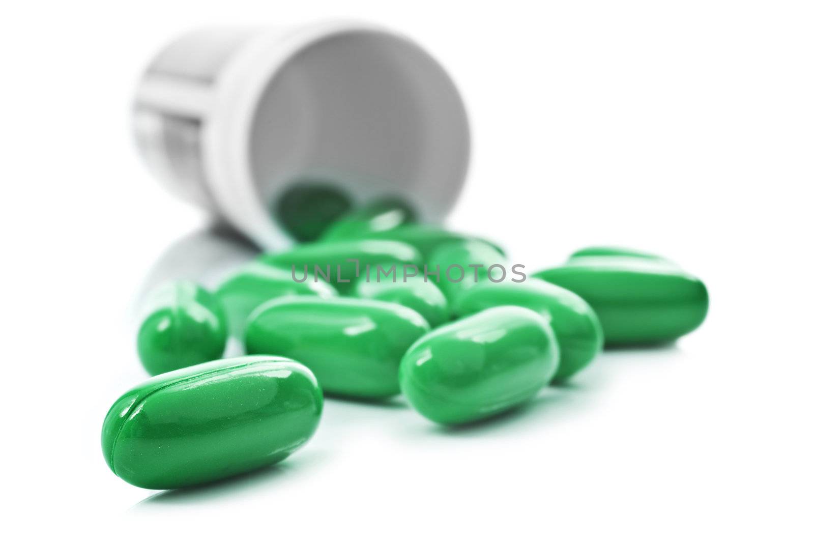 Green pills an pill bottle on white background