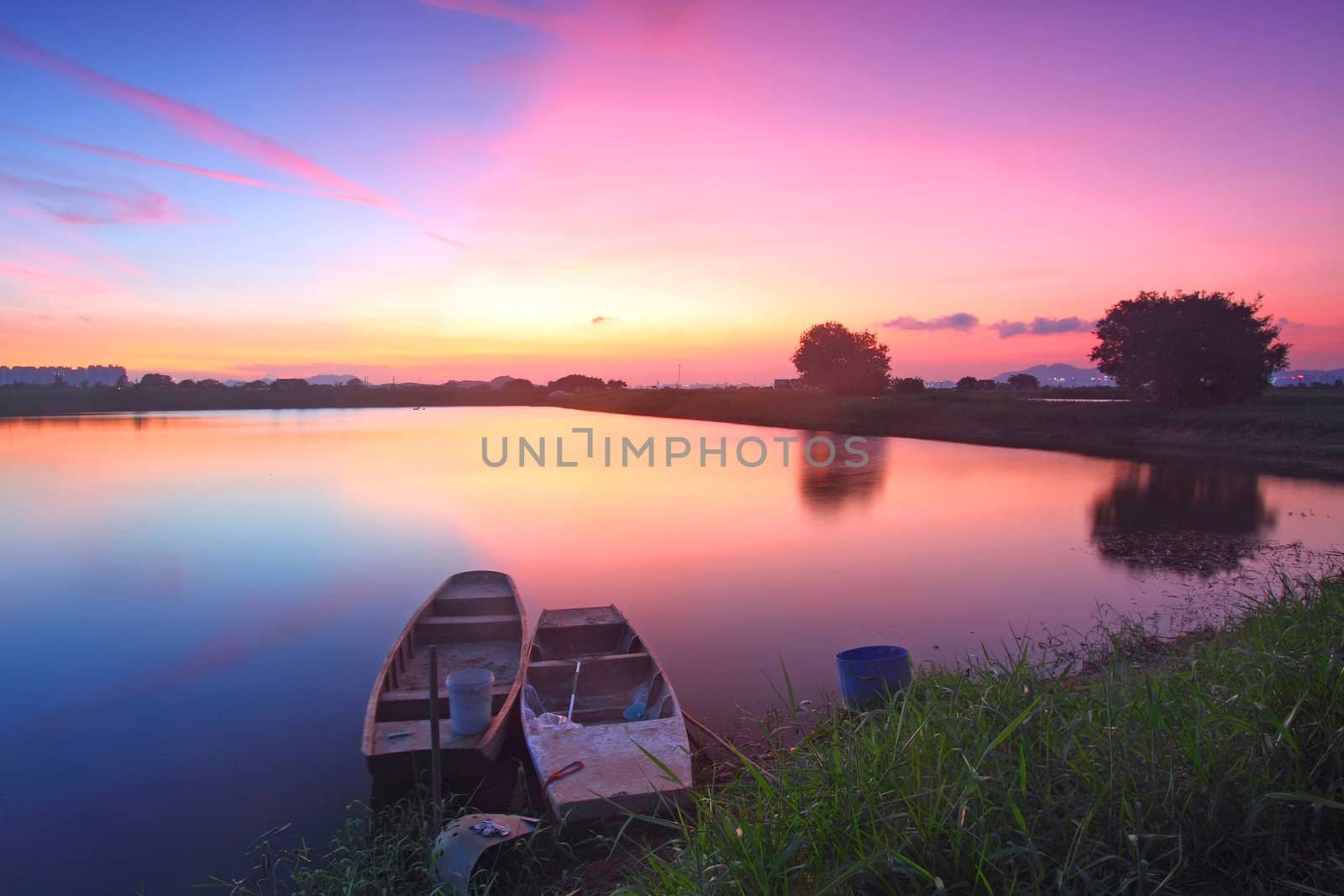 Sunset along the pond with isolated boats 
