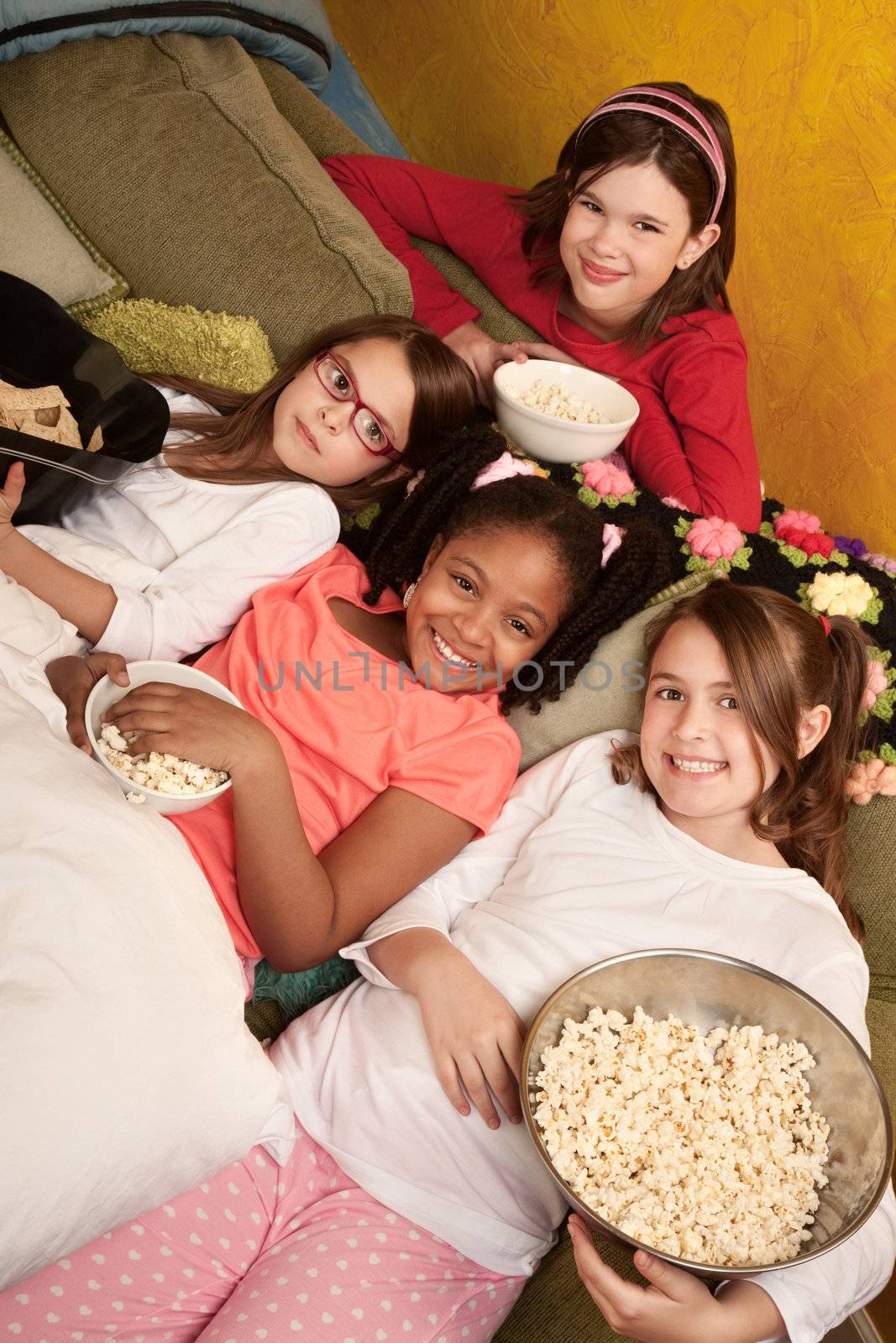 Little girls at a sleepover eat popcorn and tortilla chips 
