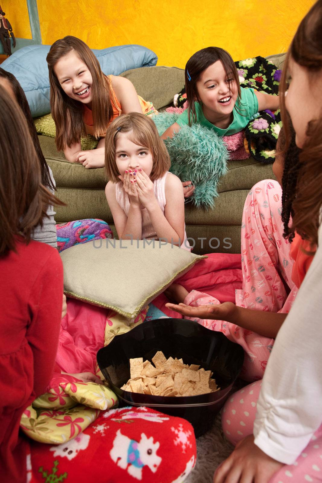 Little girls giggle and eat snacks at a sleepover