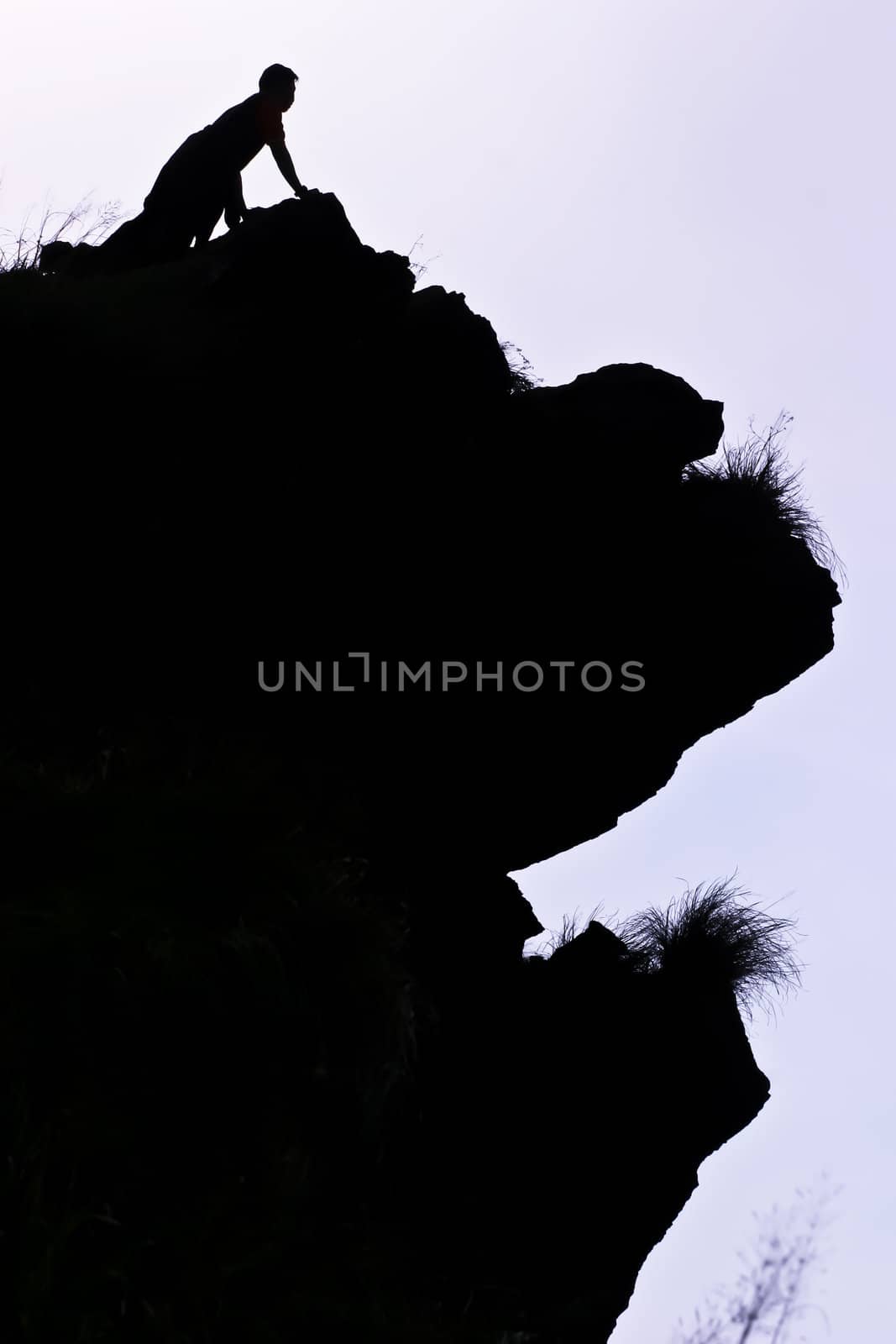 Man on peak of mountain.  by Suriyaphoto