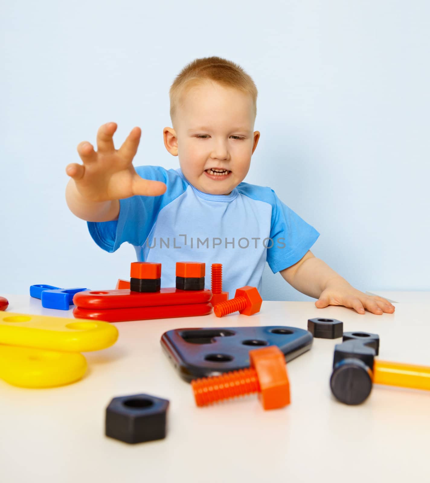 Funny kid playing with colored plastic parts