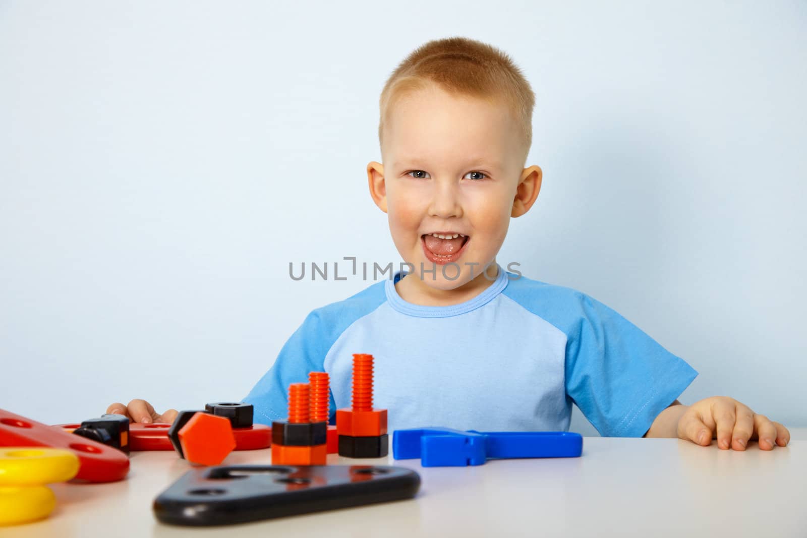 Cheery little boy playing with toys on the table