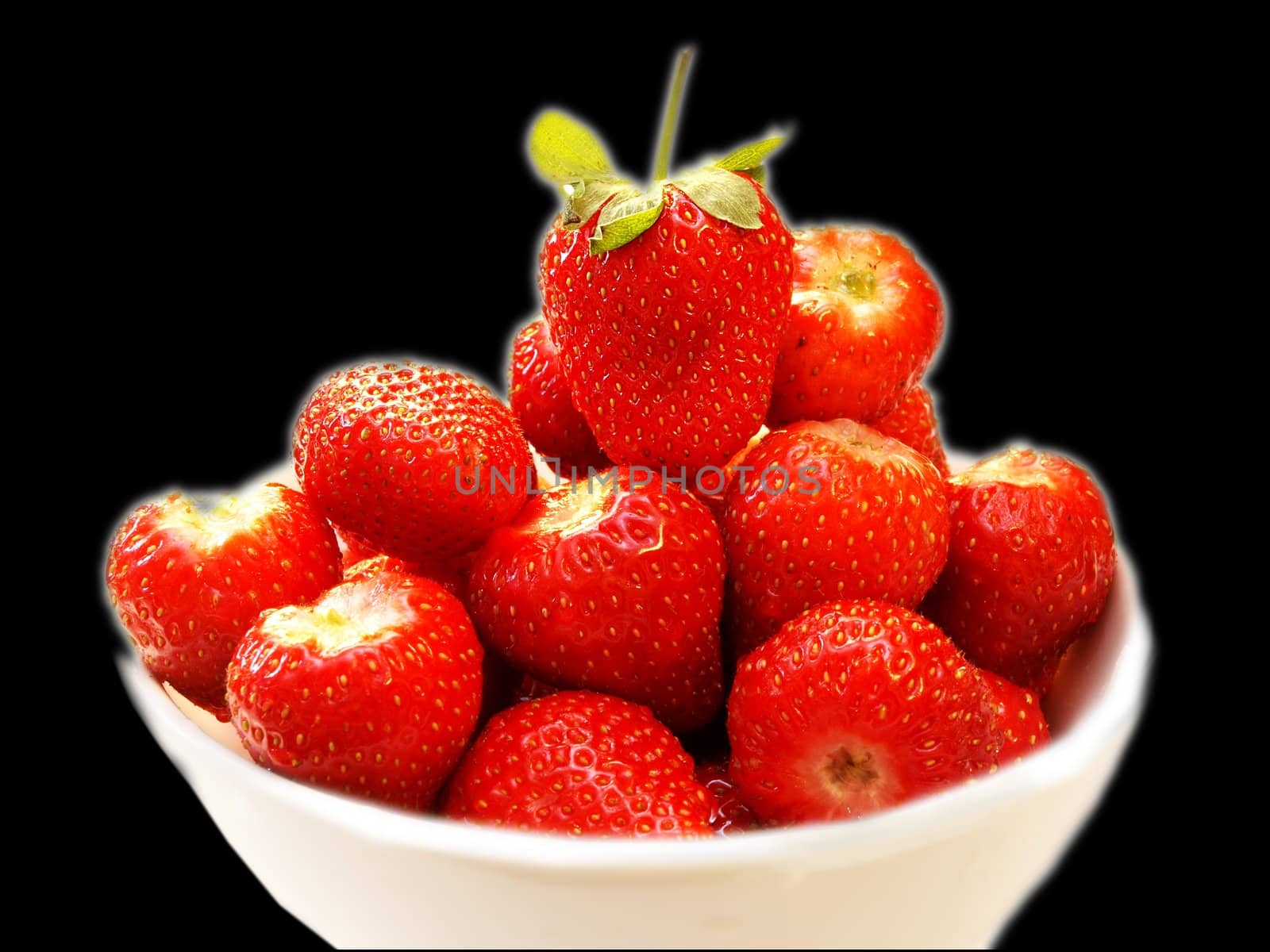 Fresh red strawberries, in a white bowl isolated towards black background