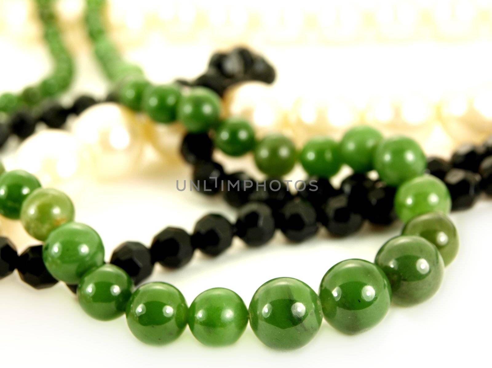 Green gemstone, white pearls, and black pearl necklace, isolated towards white background