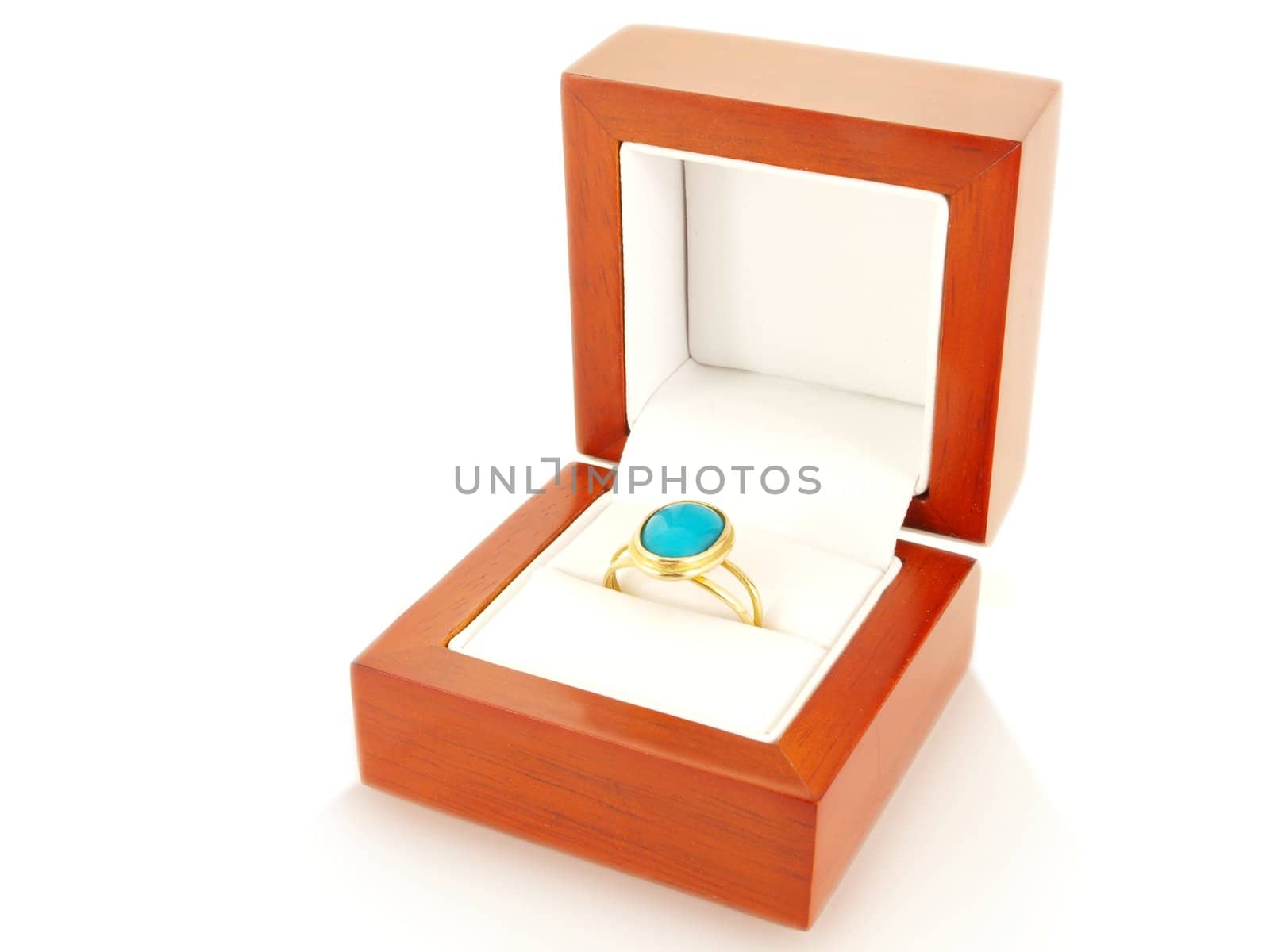 Blue gemstone on gold ring in a wooden box, isolated towards white