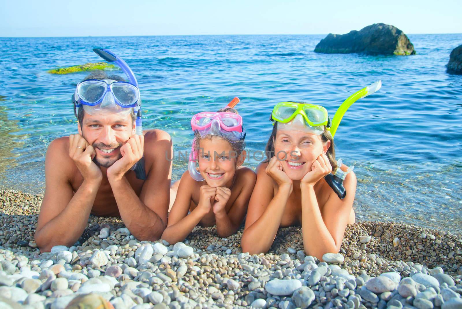 Happy family on beach with snorkles ready to have a good time swimming