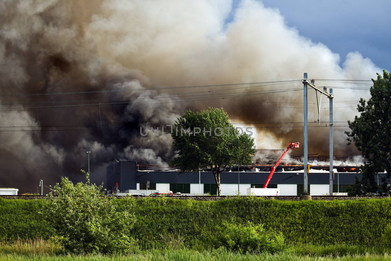 Burning recycling factory with heavy smoke and fire fighters trying to control the fire