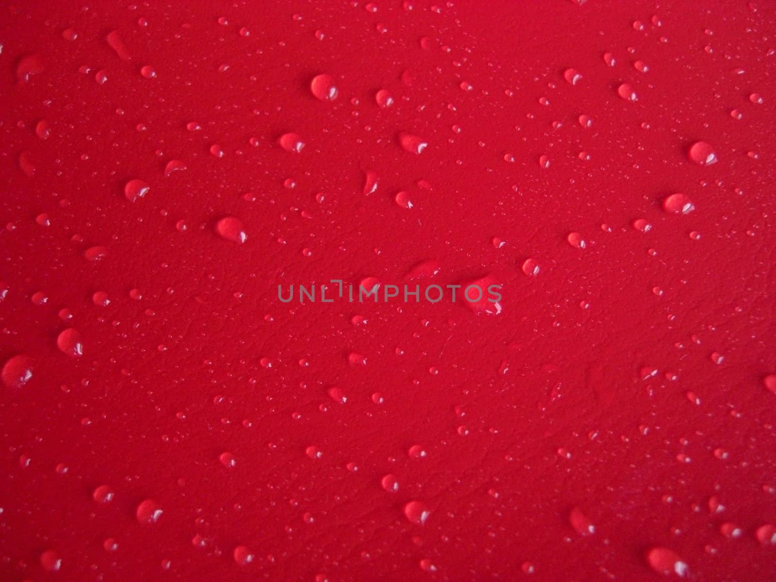 waterdrops distributed on red leathery background