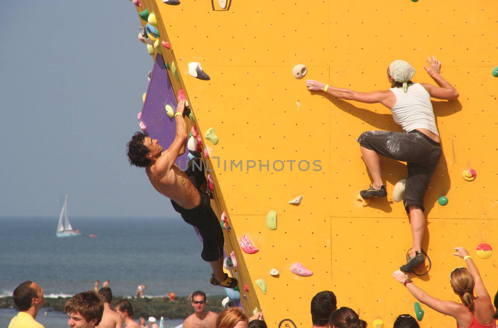 Annual Bouldering Competition on Scheveningen beach. Participants climbing artificial rock face. 