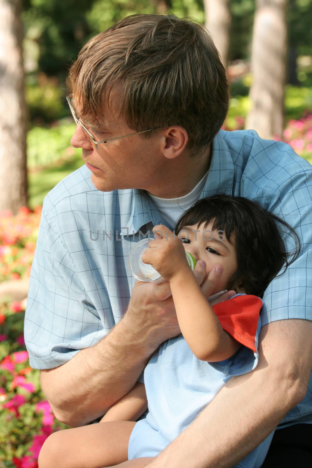 Father feeding baby a bottle in the park