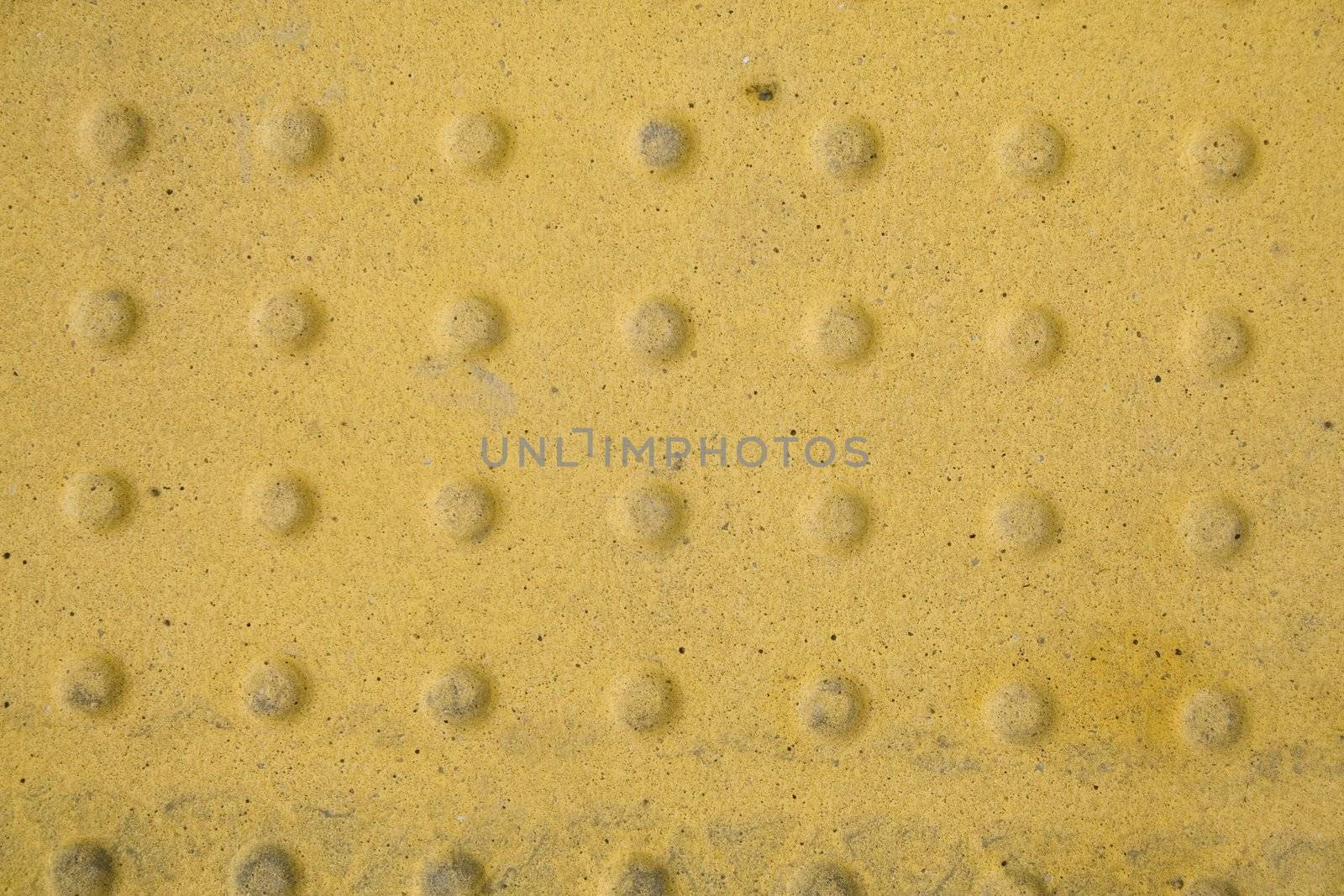 A yellow metal plate with patterned stamp.