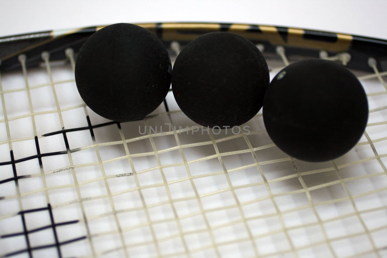 3 squash balls on a racket