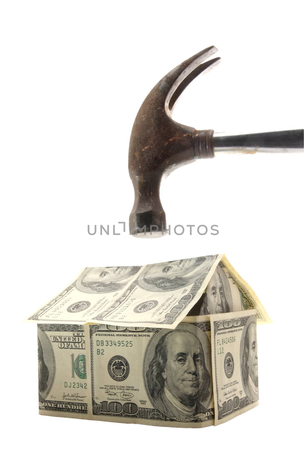 Hammer about to smash a home made out of US $100 bills - concept photo of home mortgage crisis