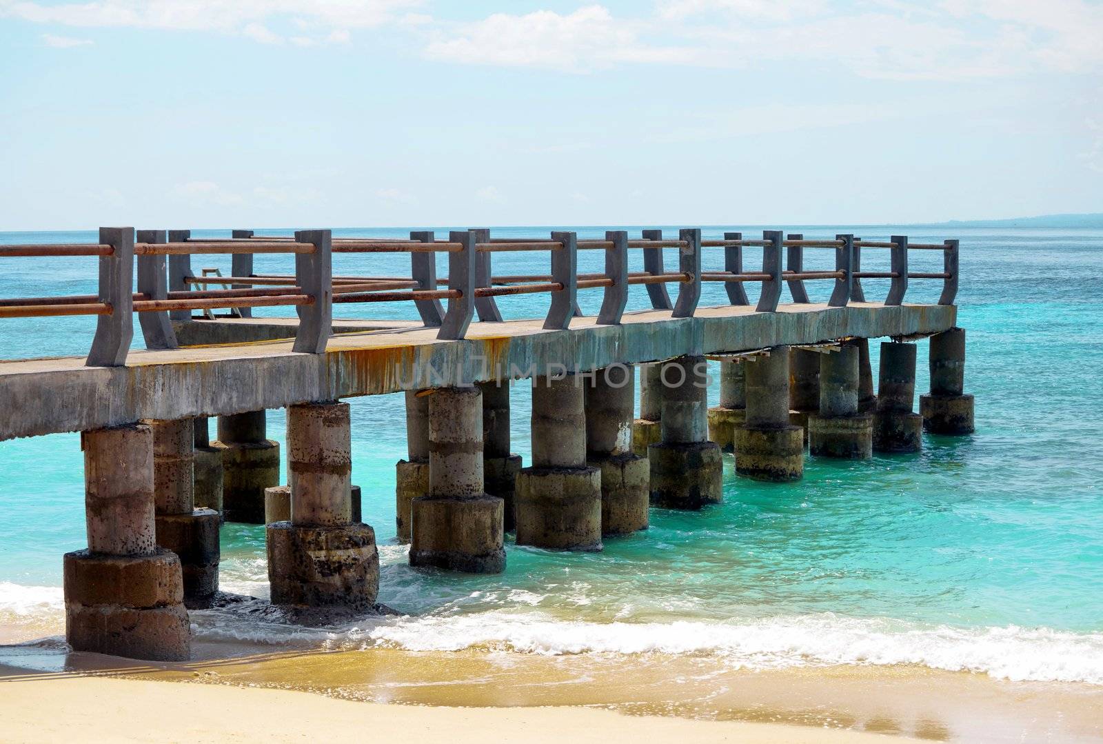 Old cement tropical pier on a sandy beach