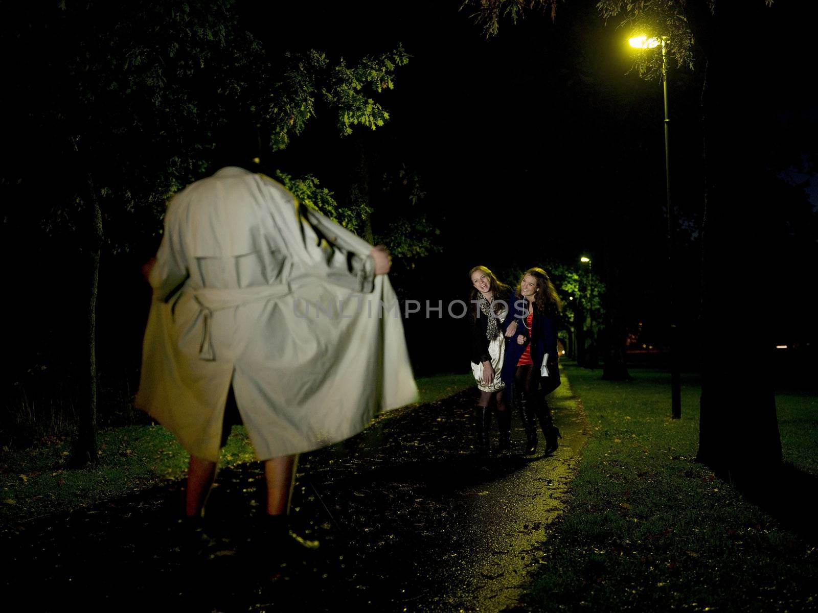 Two women laughing at a Flasher at night in the park