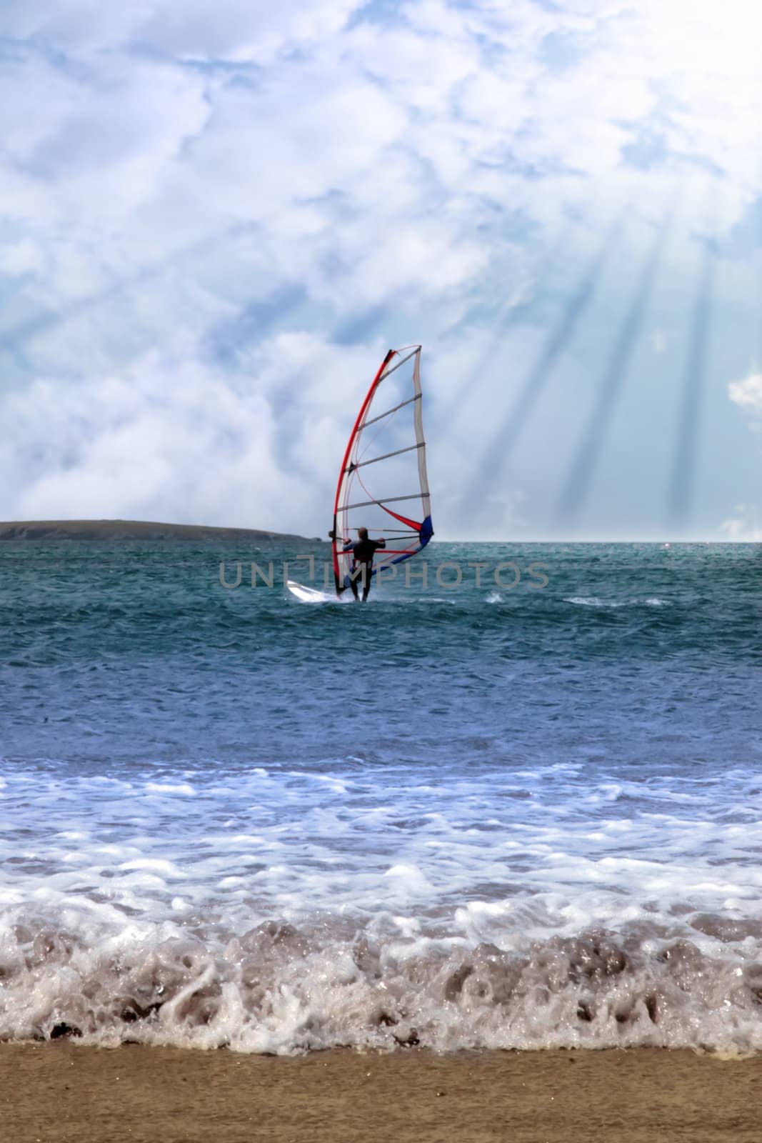 person windsurfing in the maharees in county kerry ireland during a storm in rays of sunshine