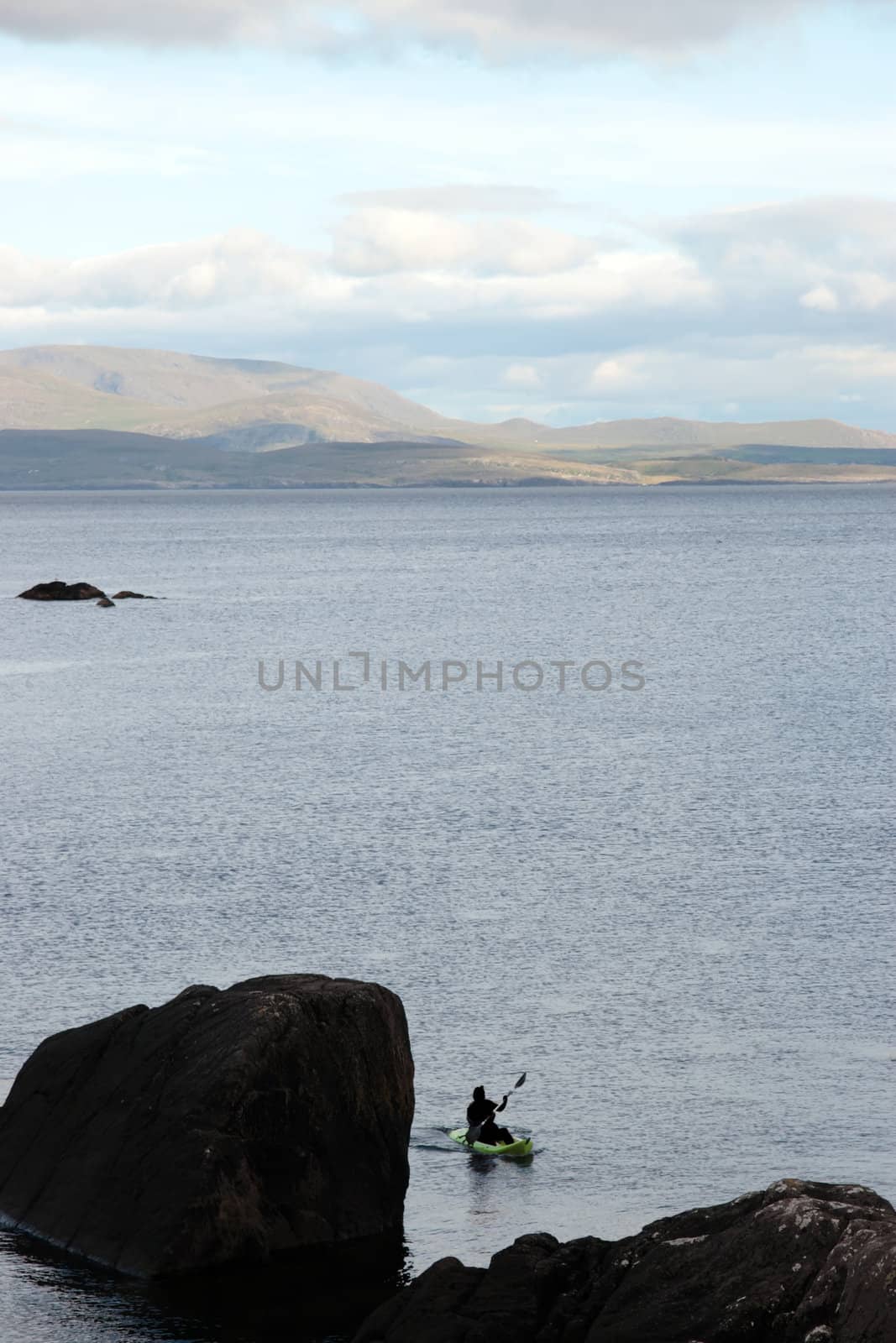 a lone green kayaker on the coast of kerry in ireland
