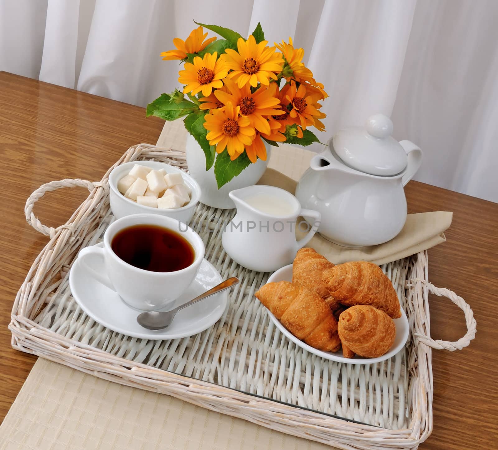 Breakfast with croissants with tea and milk on a tray