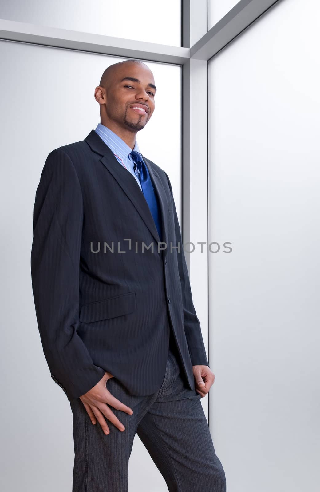 Smiling young business man beside an office window.