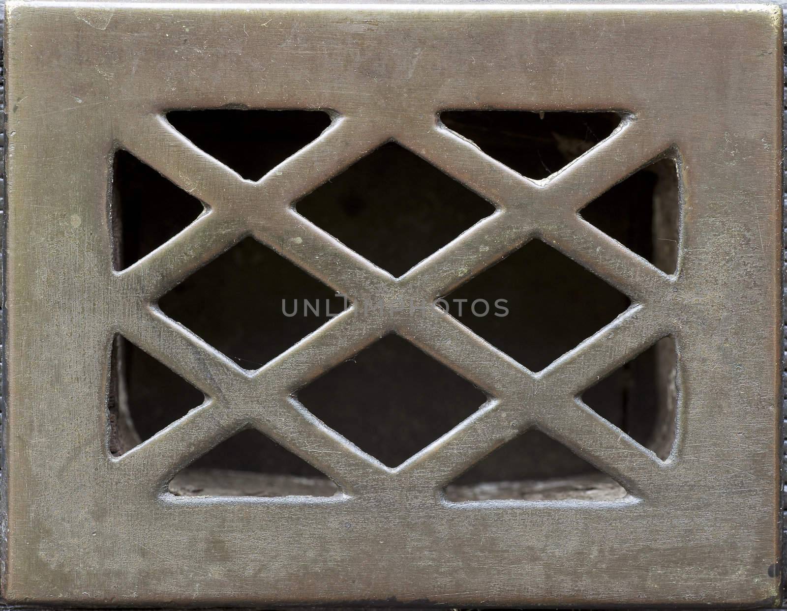 Weathered and scratched metal grate for door peep hole.