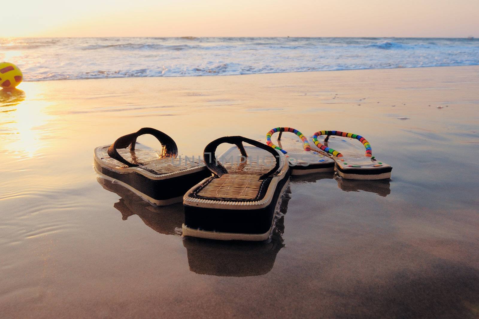 Beach sandals on the wet sandy shore