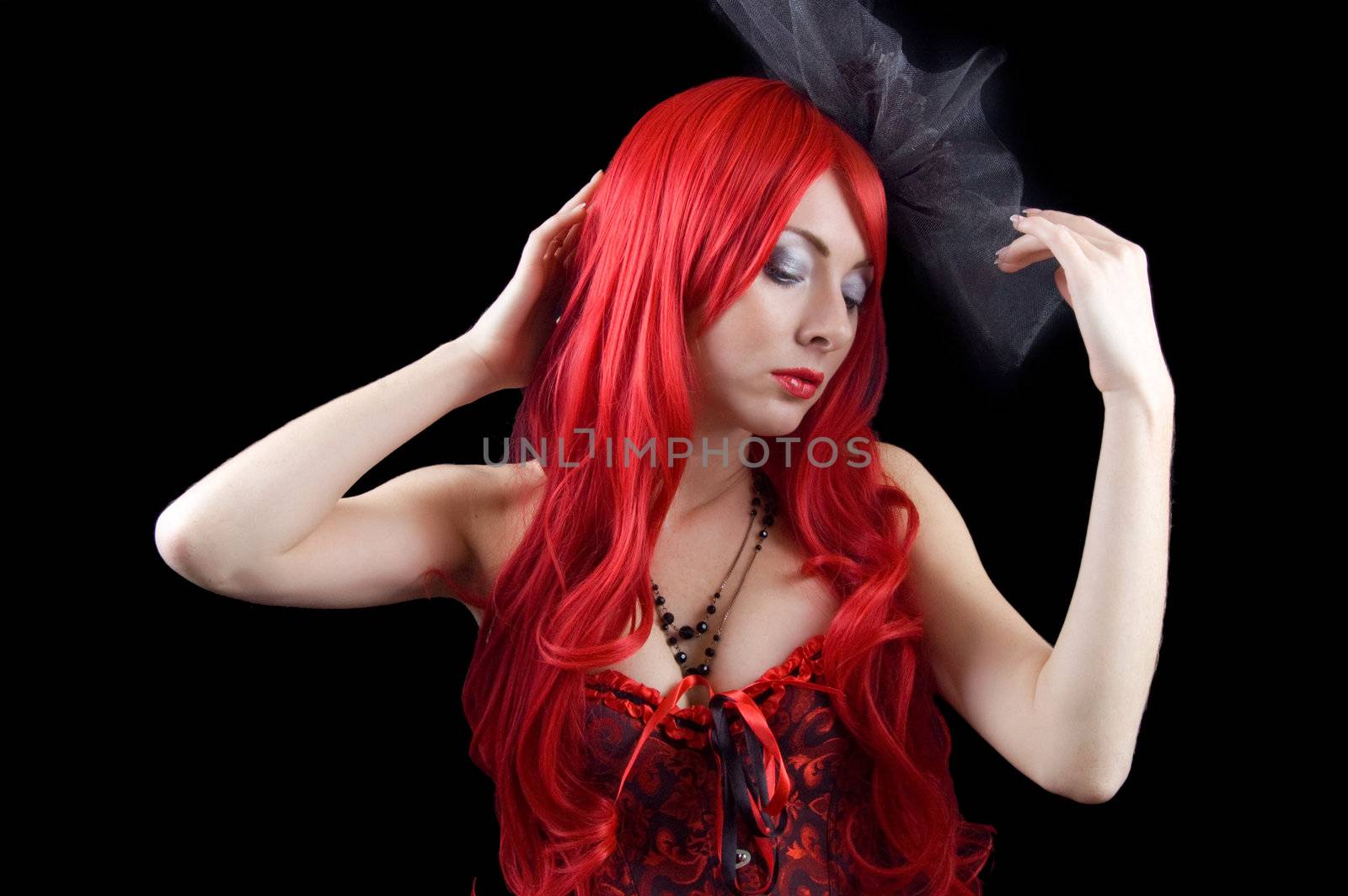 Red-headed gothic woman in black and red corset isolated on black