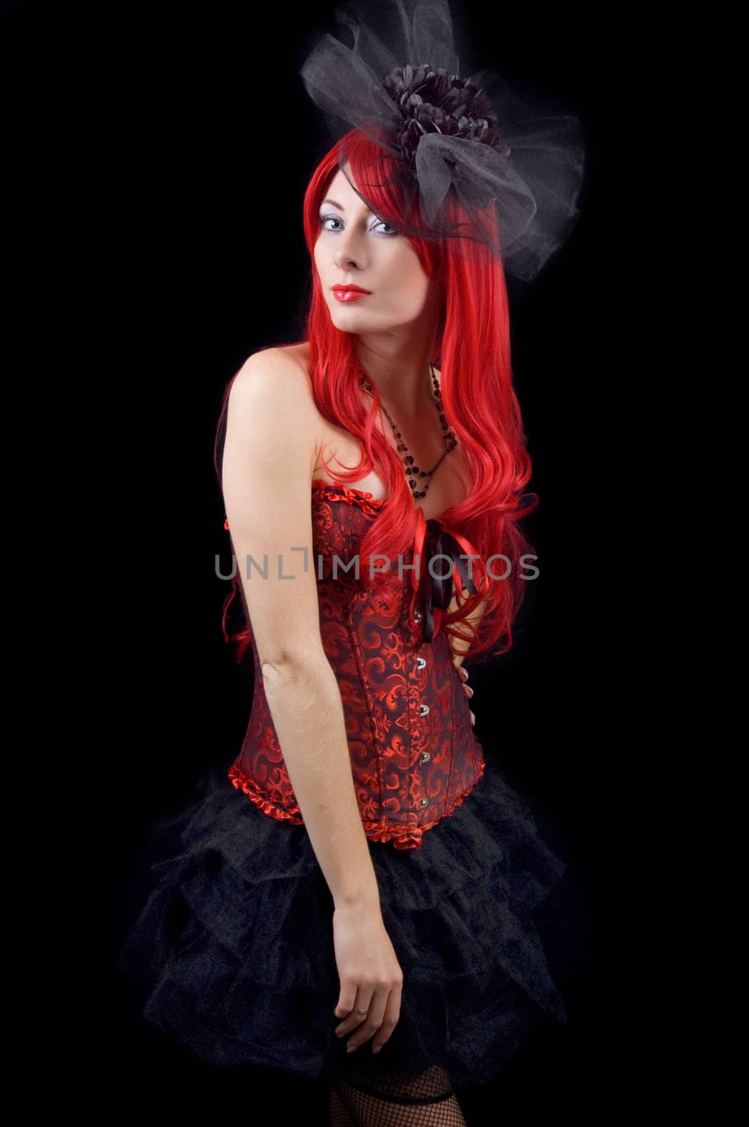 Red-headed gothic woman in black and red corset isolated on black