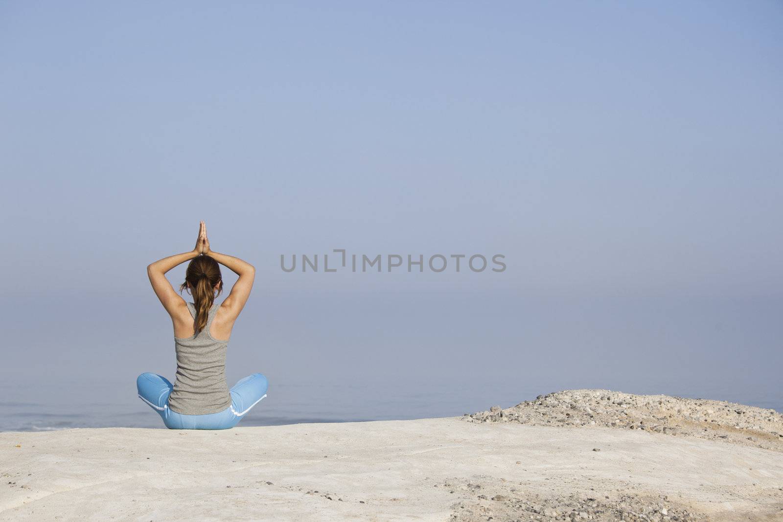 Beautiful young woman with arms open, relaxing on the beach