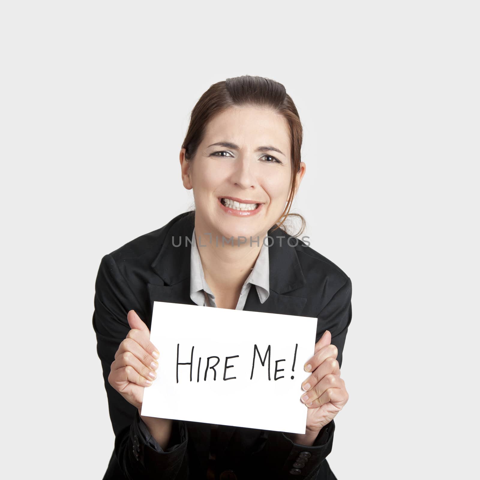 Business woman holding a card board with the text message "Hire me" and beging for a job.