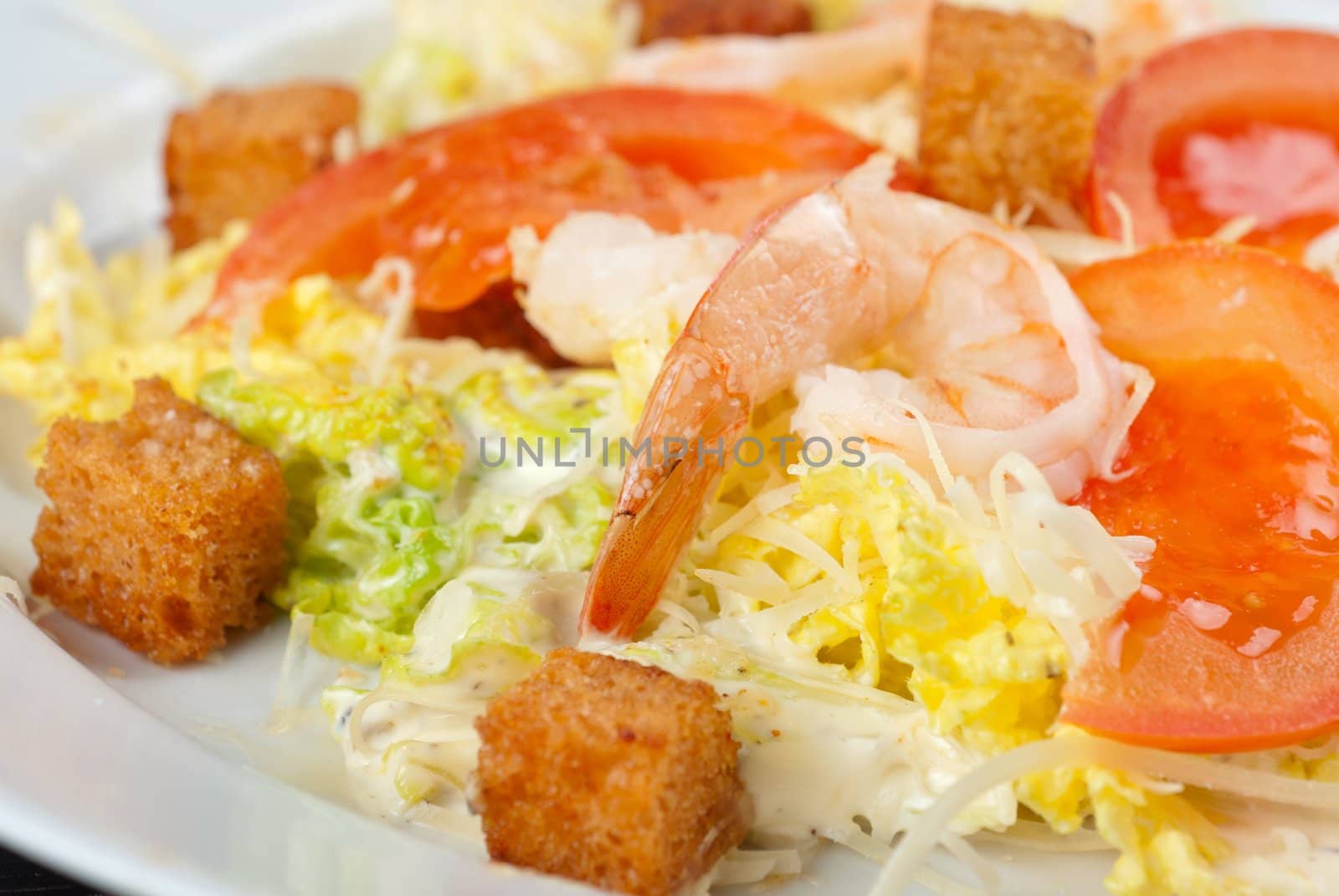 Salad of tiger shrimps, lettuce, chinese cabbage, tomato, garlic rusk, parmesan cheese and sauce