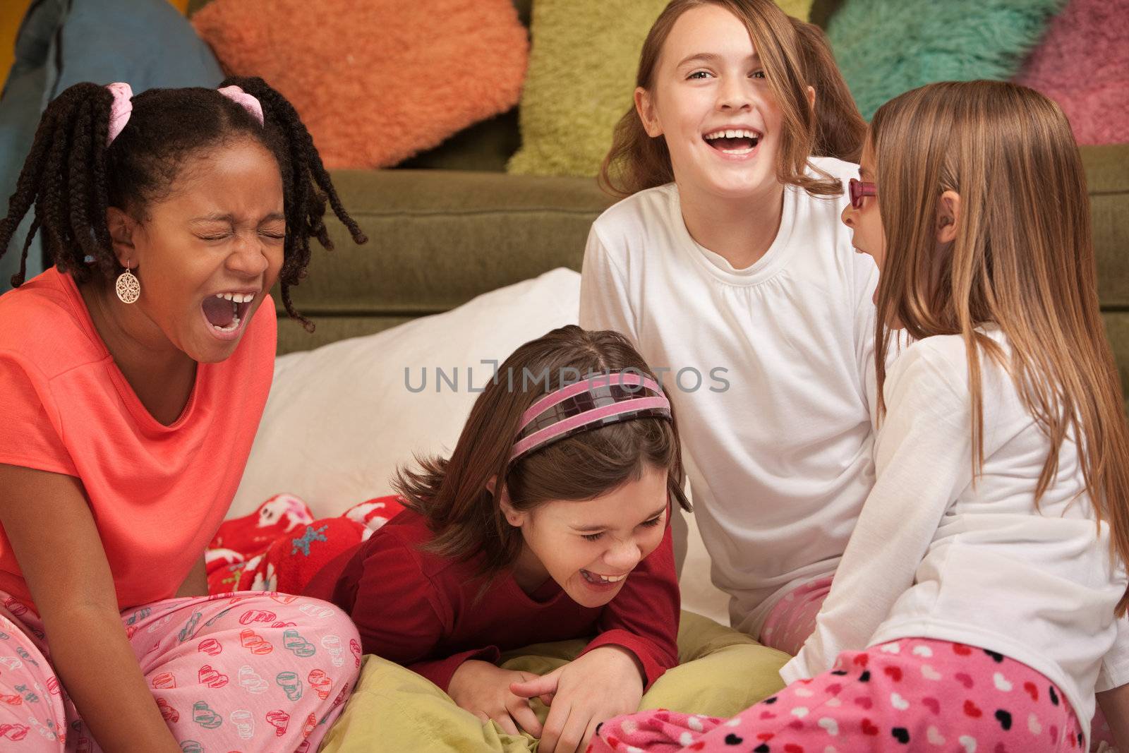 Group of four girls at a sleepover laugh out loud 