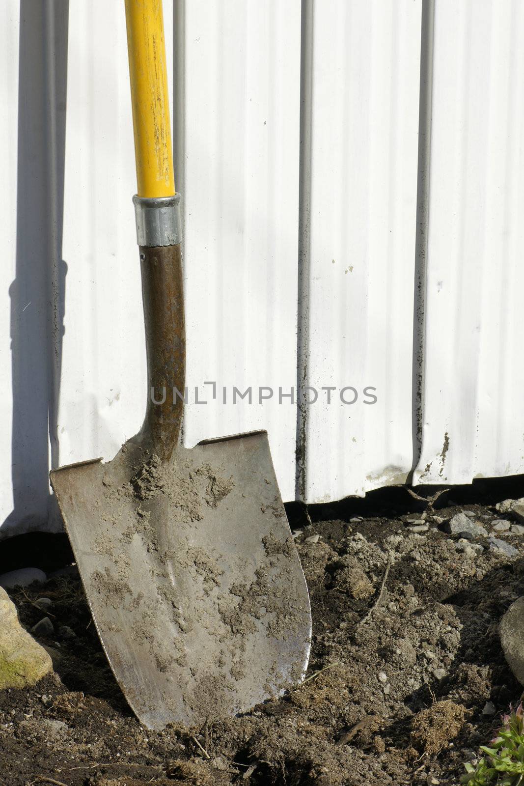 Shovel in earth against garden shed by Mirage3