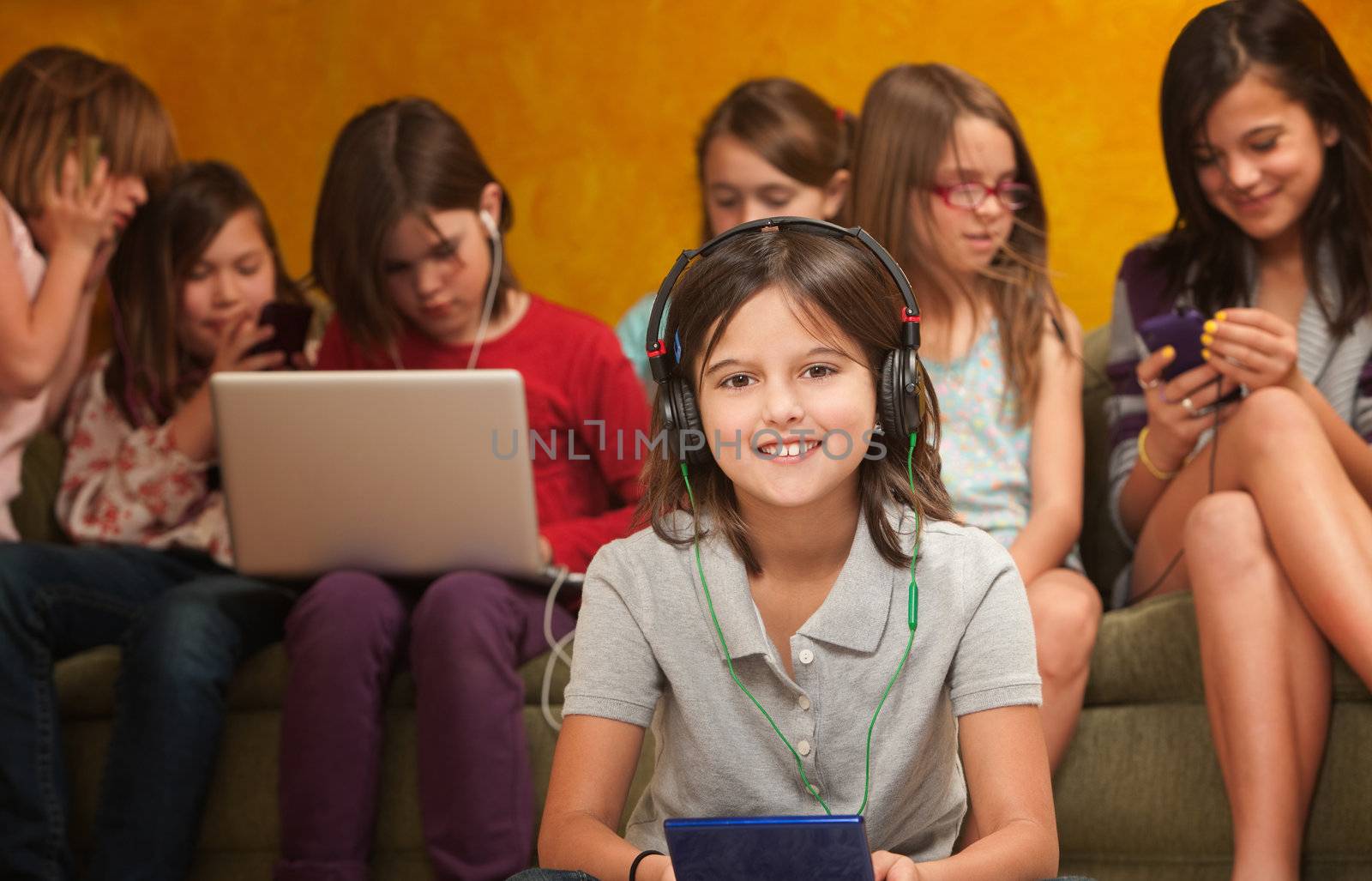 Smiling little girl with video game on a console with friends behind her