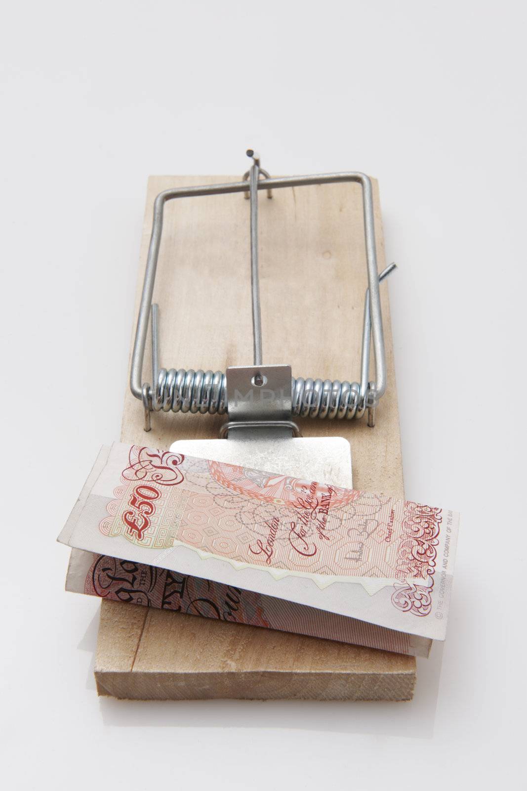 fifty pound note set on a mousetrap on white background