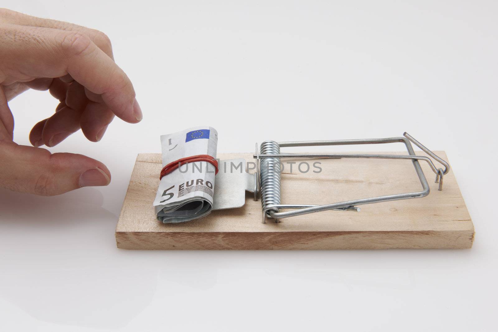 Male hand taking rolled up euro bills from mousetrap