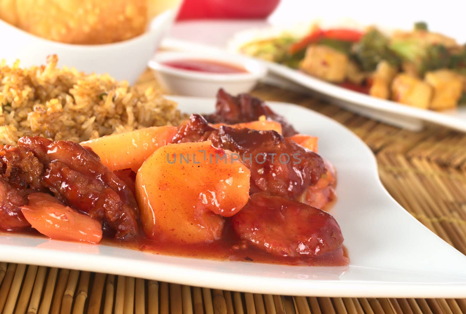 Chinese sweet and sour with pineapple and chicken pieces with rice in the back (Selective Focus, Focus on the pineapple and chicken in the front)