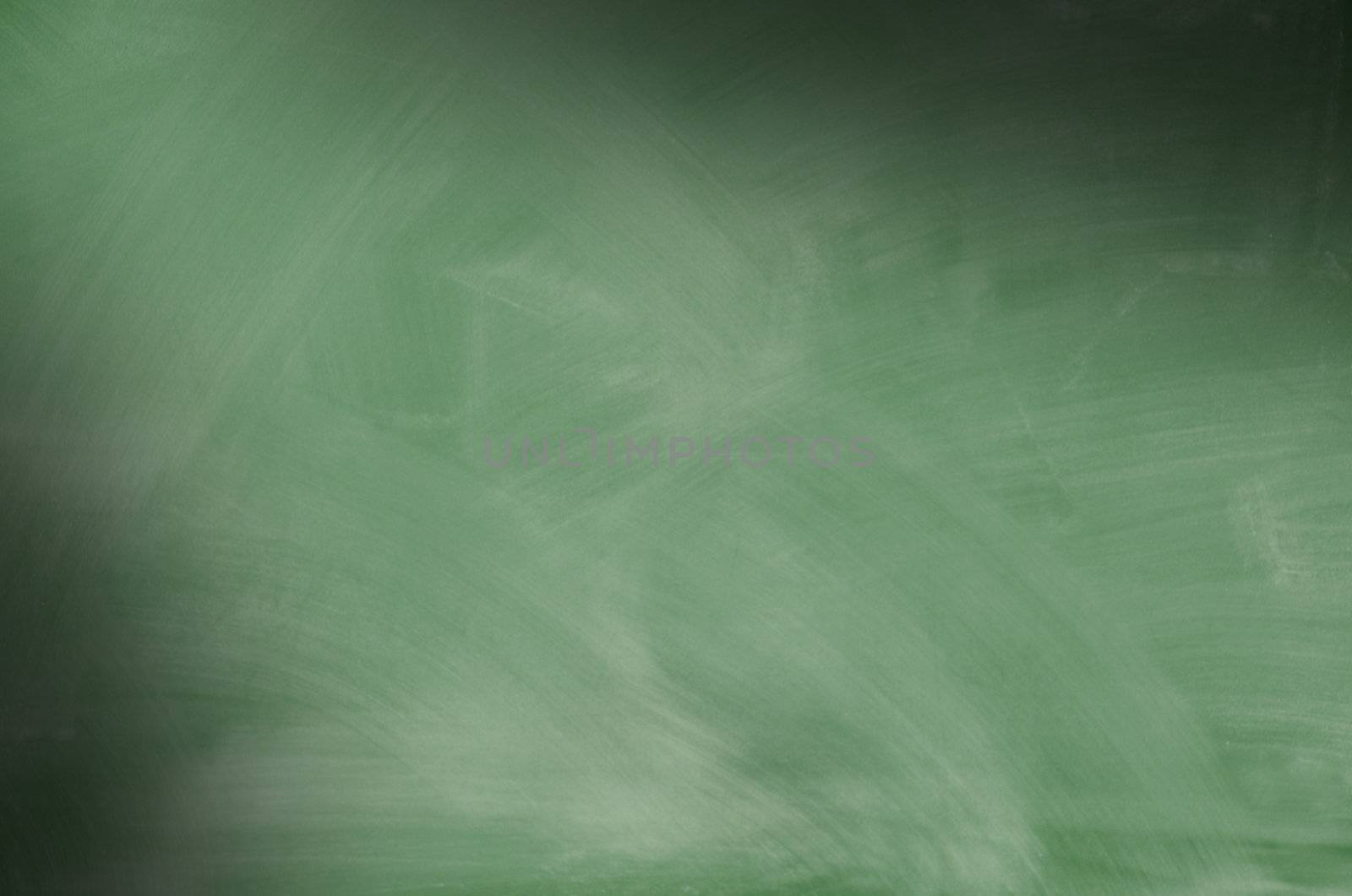 Green chalkboard with smeared chalk eraser marks lit diagonally