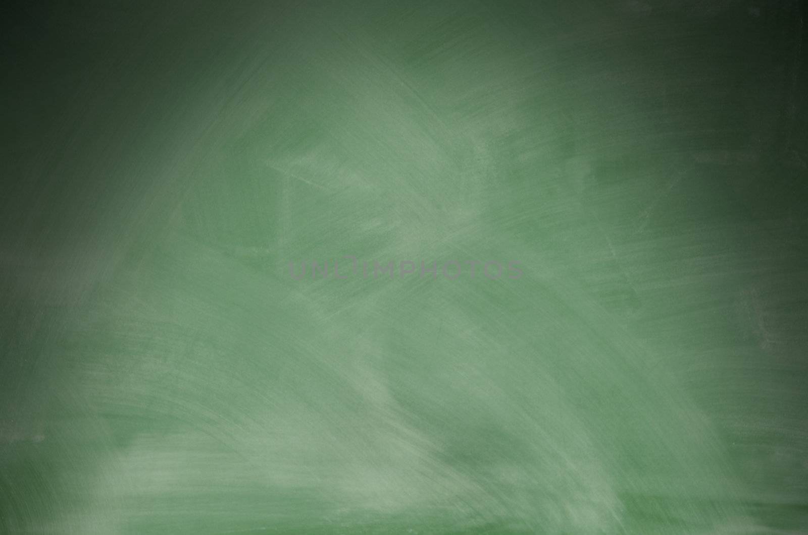 Green chalkboard with eraser marks lit dramatically from above