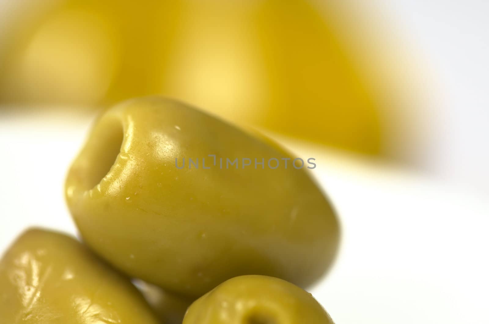 Closeup of a green olive with olive oil in the back (Very Shallow Depth of Field, Focus on the front close to the opening of the top olive)