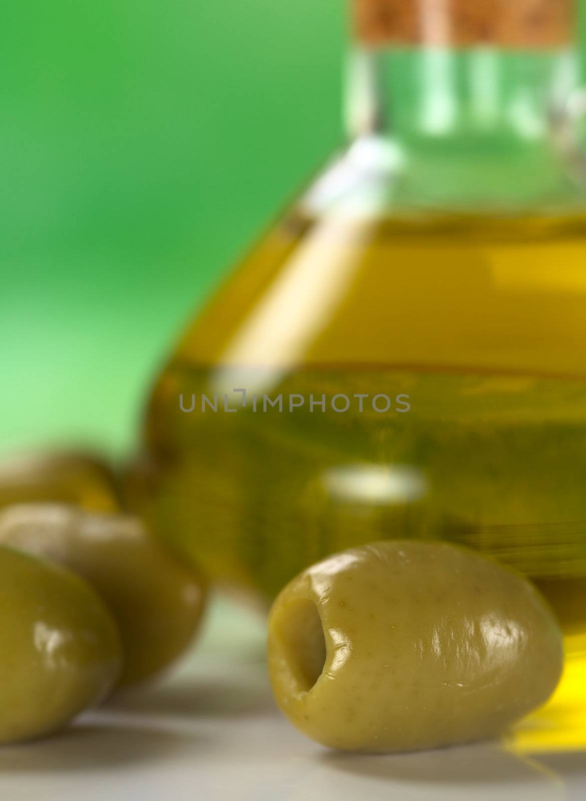 Green olive with olive oil in the back (Very Shallow Depth of Field, Focus on the front close to the opening of the right olive)