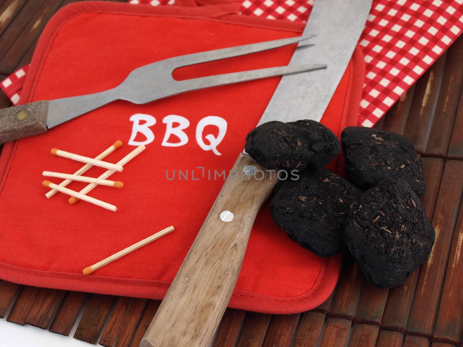 Items used for a Barbeque, including charcoal, wooden matches and a bright red pot holder.