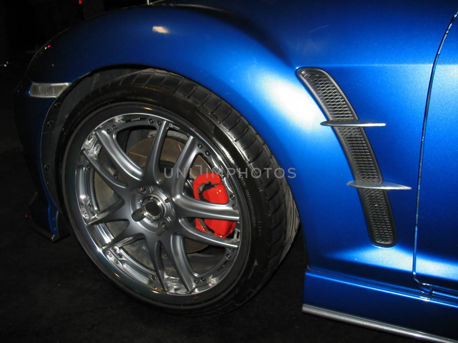 A closeup of the front quarter of a blue import sportscar.