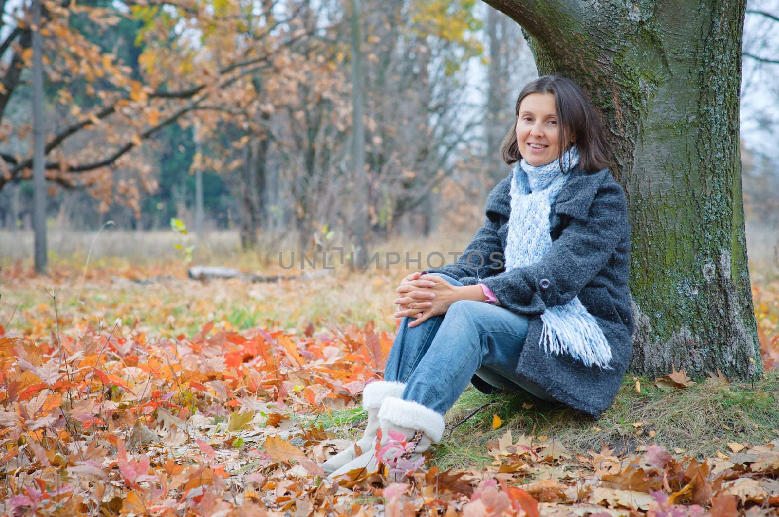 Cute happy young woman sitting in the autumn park.