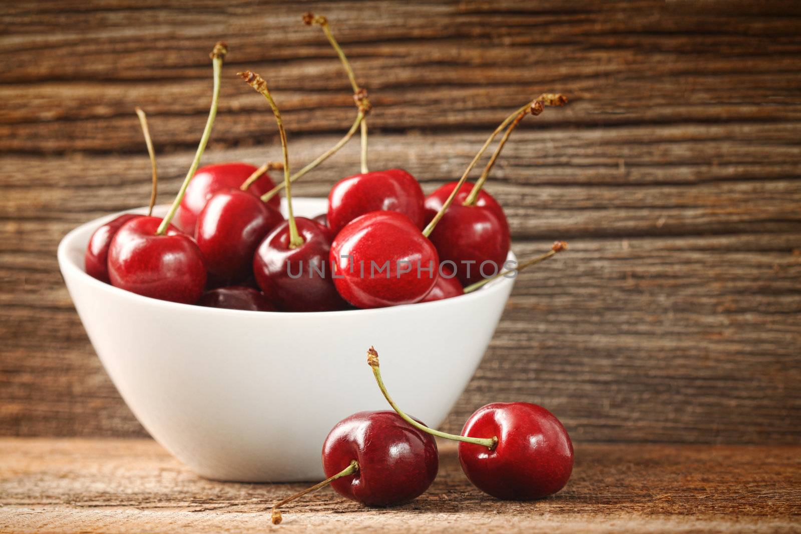 Red cherries in bowl on old barn wood
