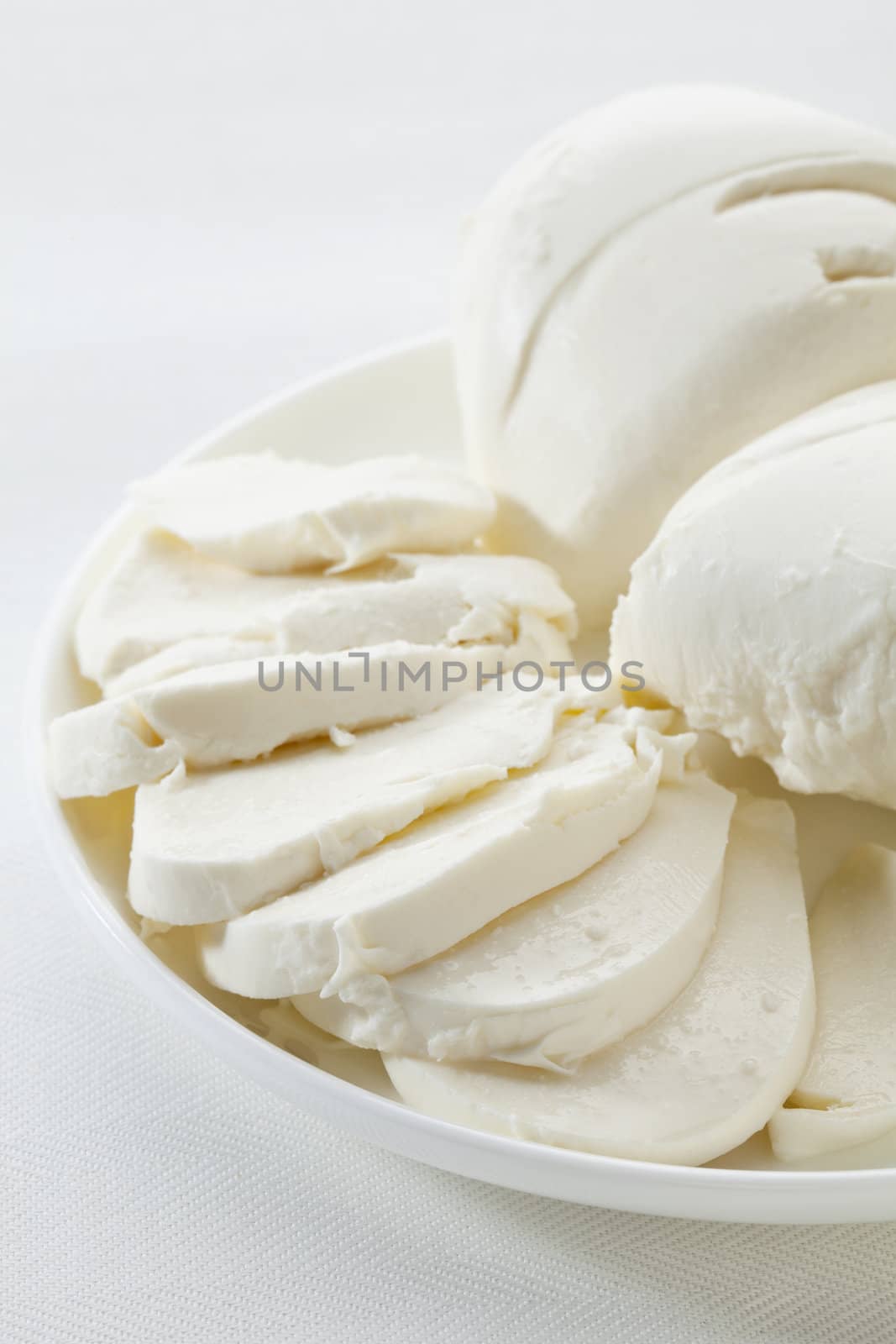 slices of fresh mozzarella cheese on white plate and tablecloth