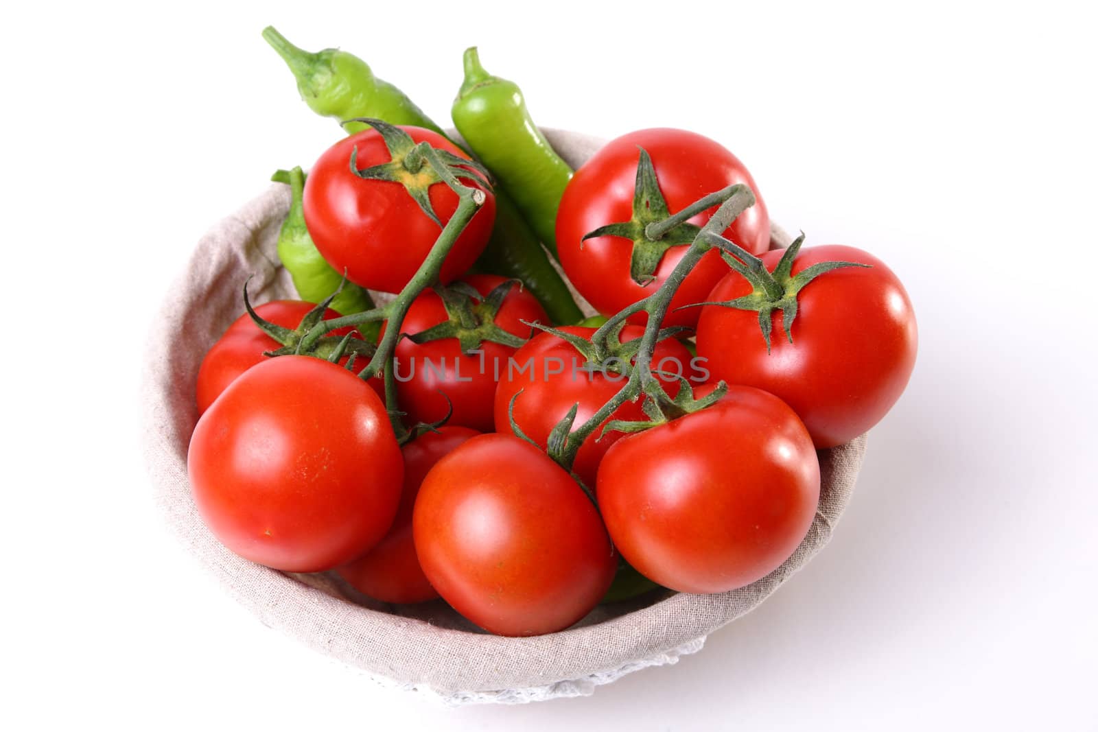 Red tomatoes and green peperoni in basket on white background